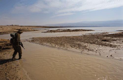 C_NB-Israeli-soldier-walks-in-water-at-point-where-Jordan-River-and-Dead-Sea-meet-RTXCYN0
