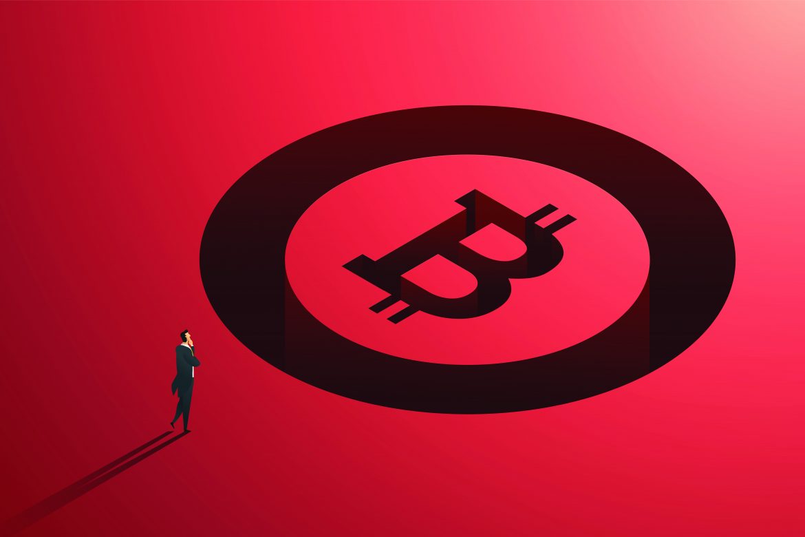 Businessman standing in front of giant bitcoin token.