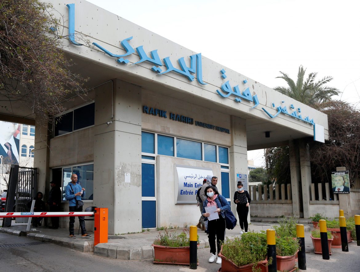 People wearing face masks walk outside Rafik Hariri hospital, where Lebanon’s first coronavirus case is being quarantined, in Beirut