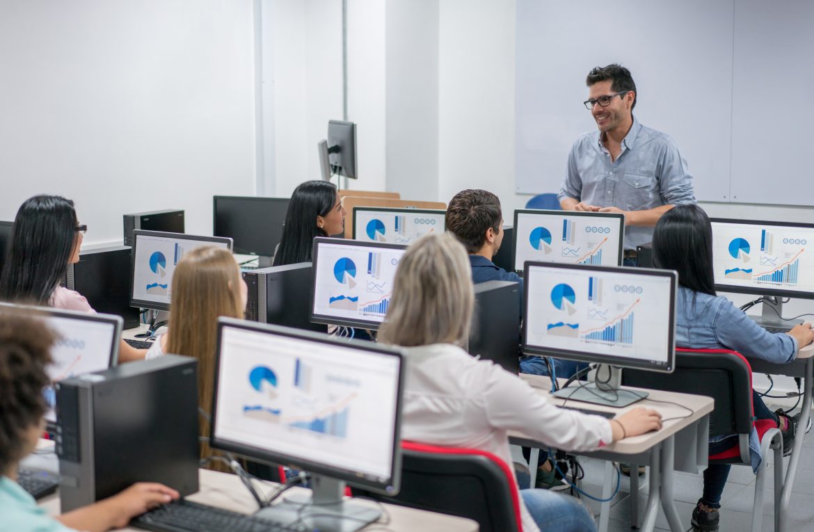 Teacher giving an IT class at school to a group of students